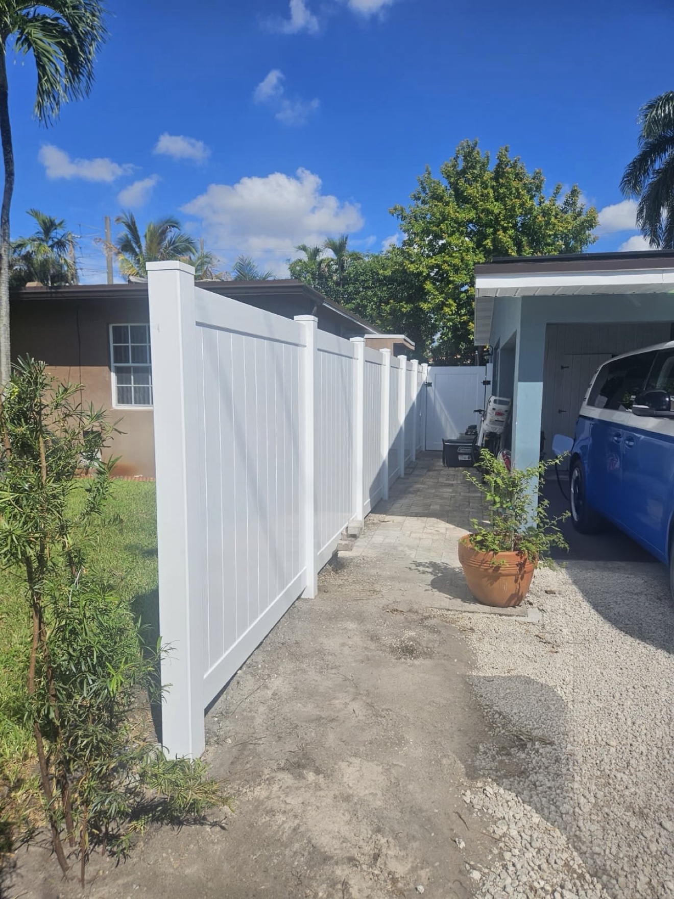 Completed white PVC privacy fence along the driveway