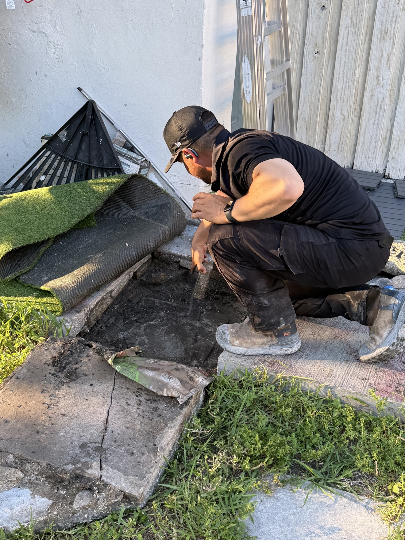 Worker crouching beside the house wall during septic work