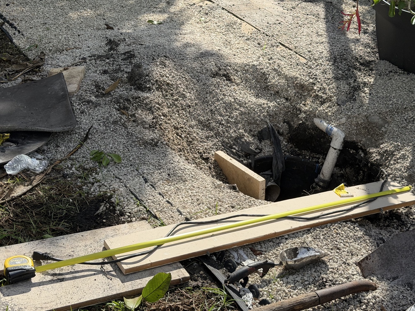 Sump drainage excavation with black basin, piping and measuring equipment