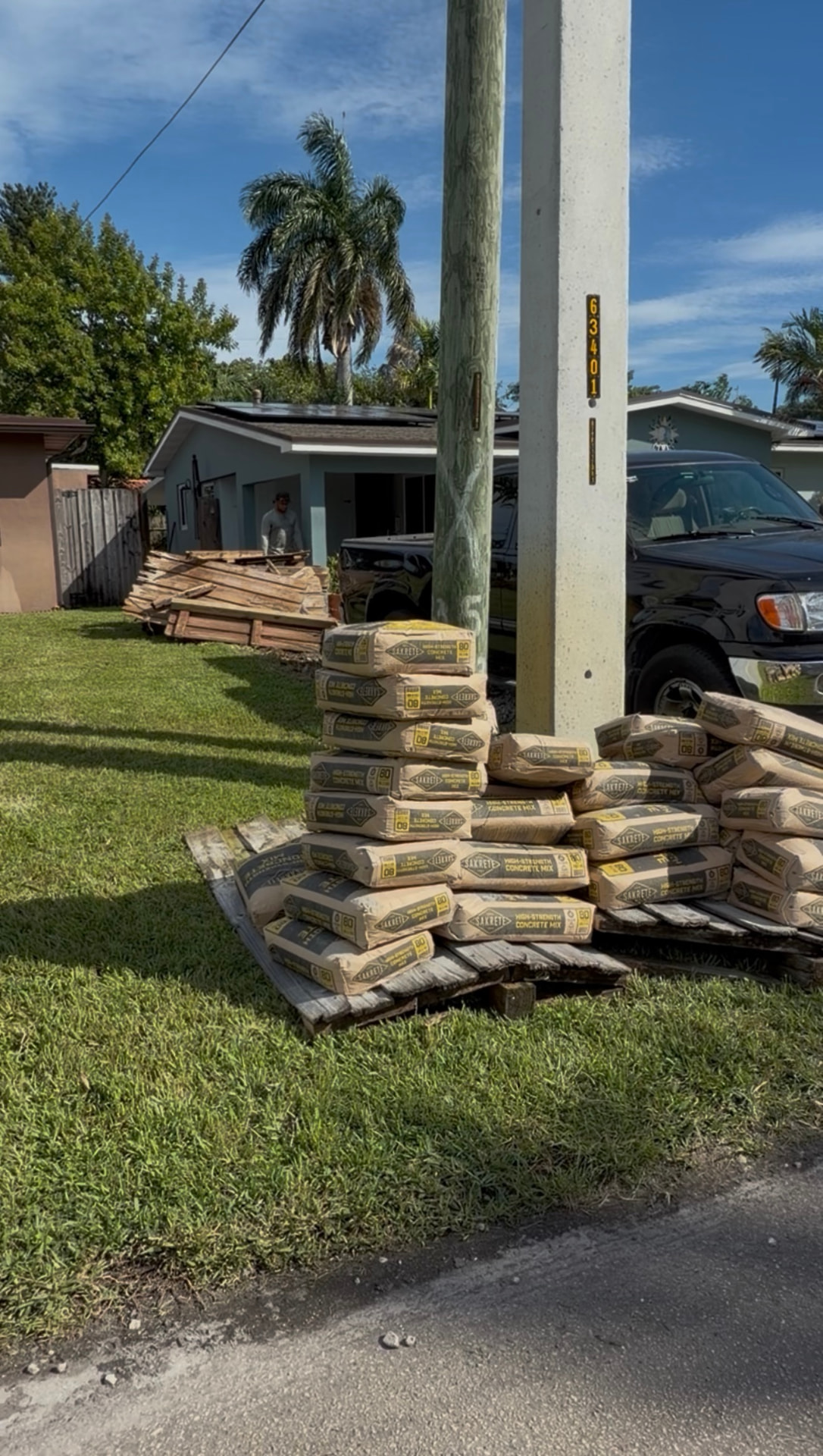 Cement bags and demolished wooden fencing before PVC fence installation