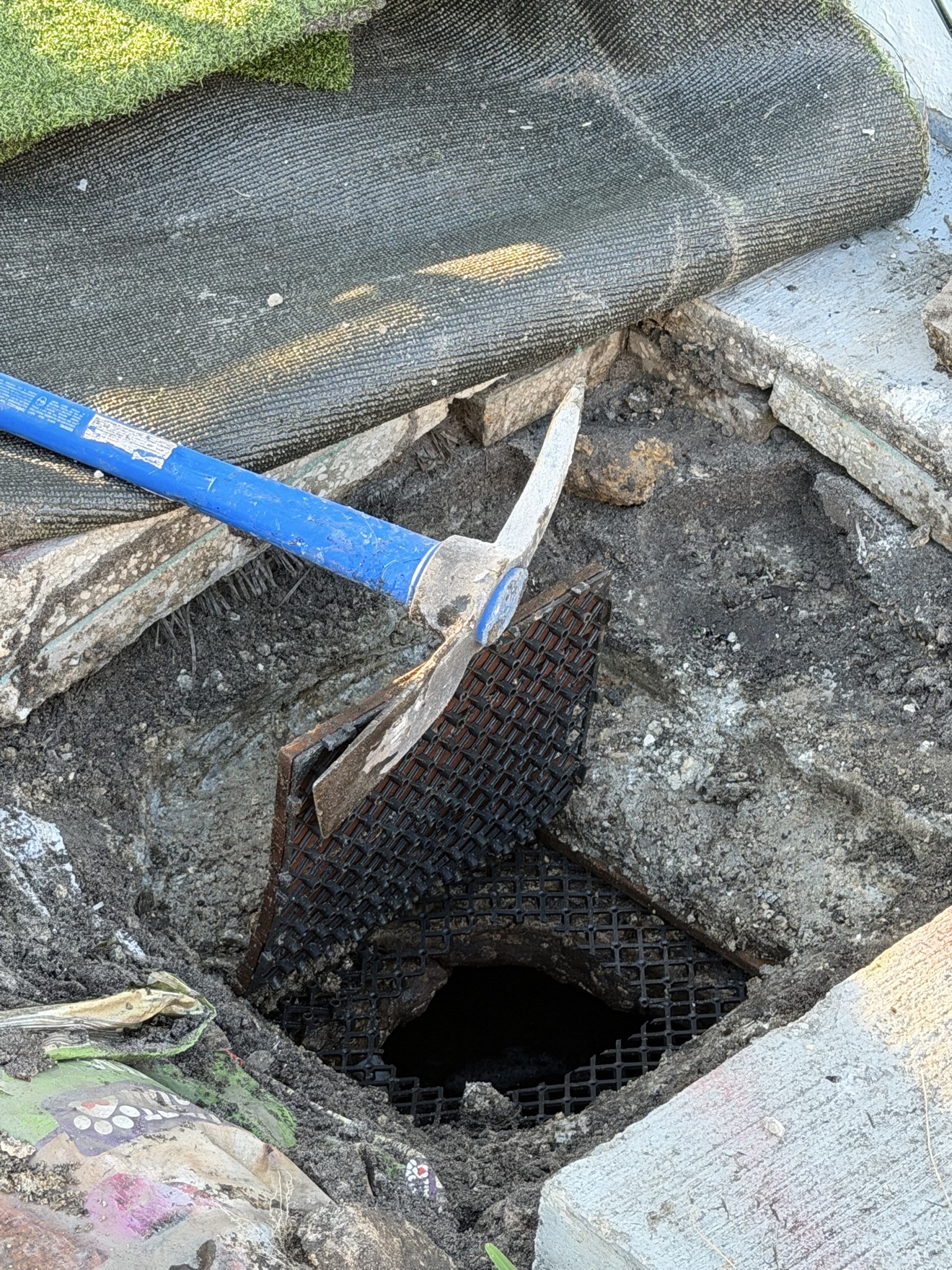 Septic work excavation with exposed opening, grate and pickaxe